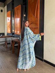 Woman in a floral dress standing in a modern interior setting with wooden panels.