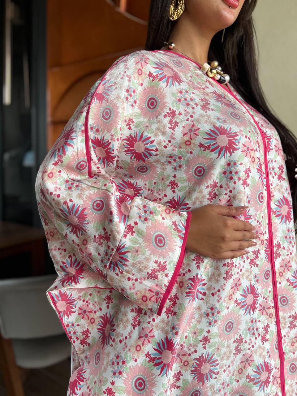 Woman wearing a floral dress with pink and green patterns.